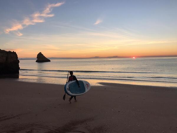 Met sup-board de zee in tijdens zonsopkomst in Portugal